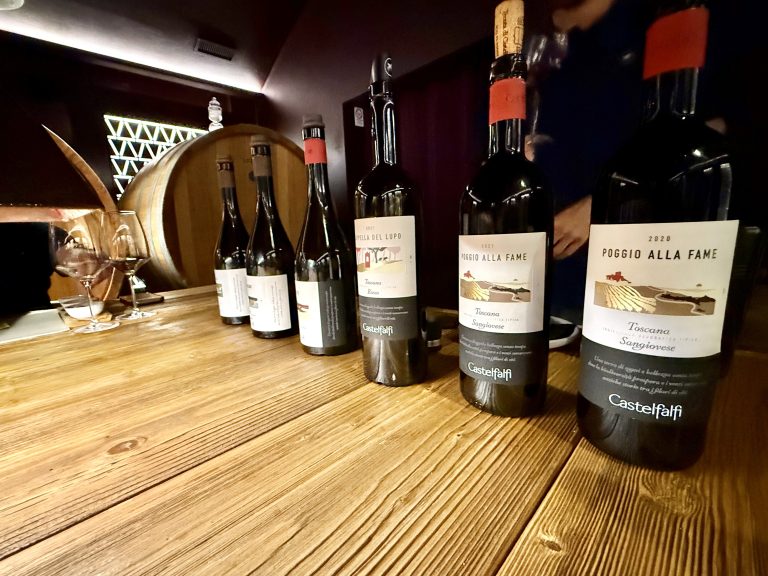Wine bottles and barrels at a Castelfalfi Tuscany vineyard wine tasting, offering a luxury travel experience and lifestyle inspiration