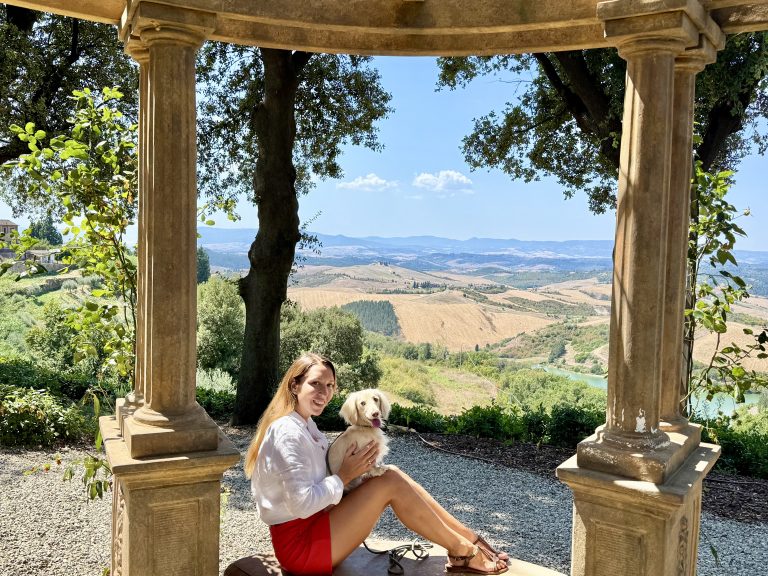 Woman 40 years old enjoying a luxury escape at Castelfalfi in Tuscany with her mini cream dachshund, reflecting reinvention and elegant lifestyle for First Class Boarding Pass Signature Escapes.