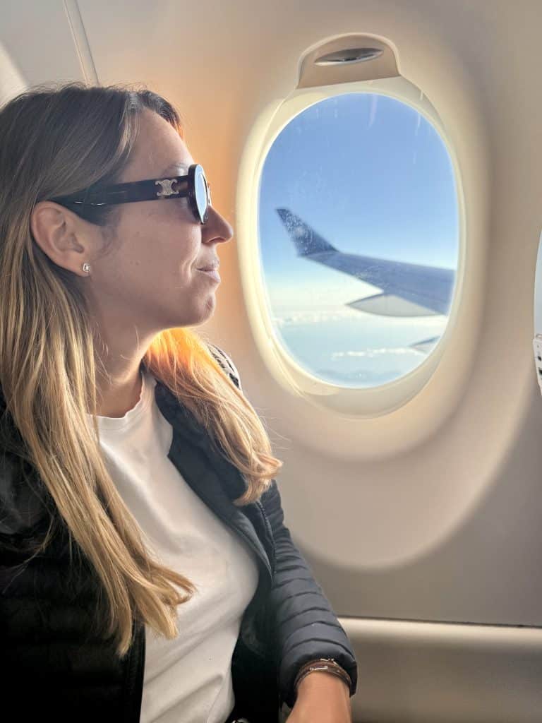 Midlife Reinvention, a 40-year-old woman sitting by the plane window with sky and wing view, symbolising the journey of personal and professional transformation.